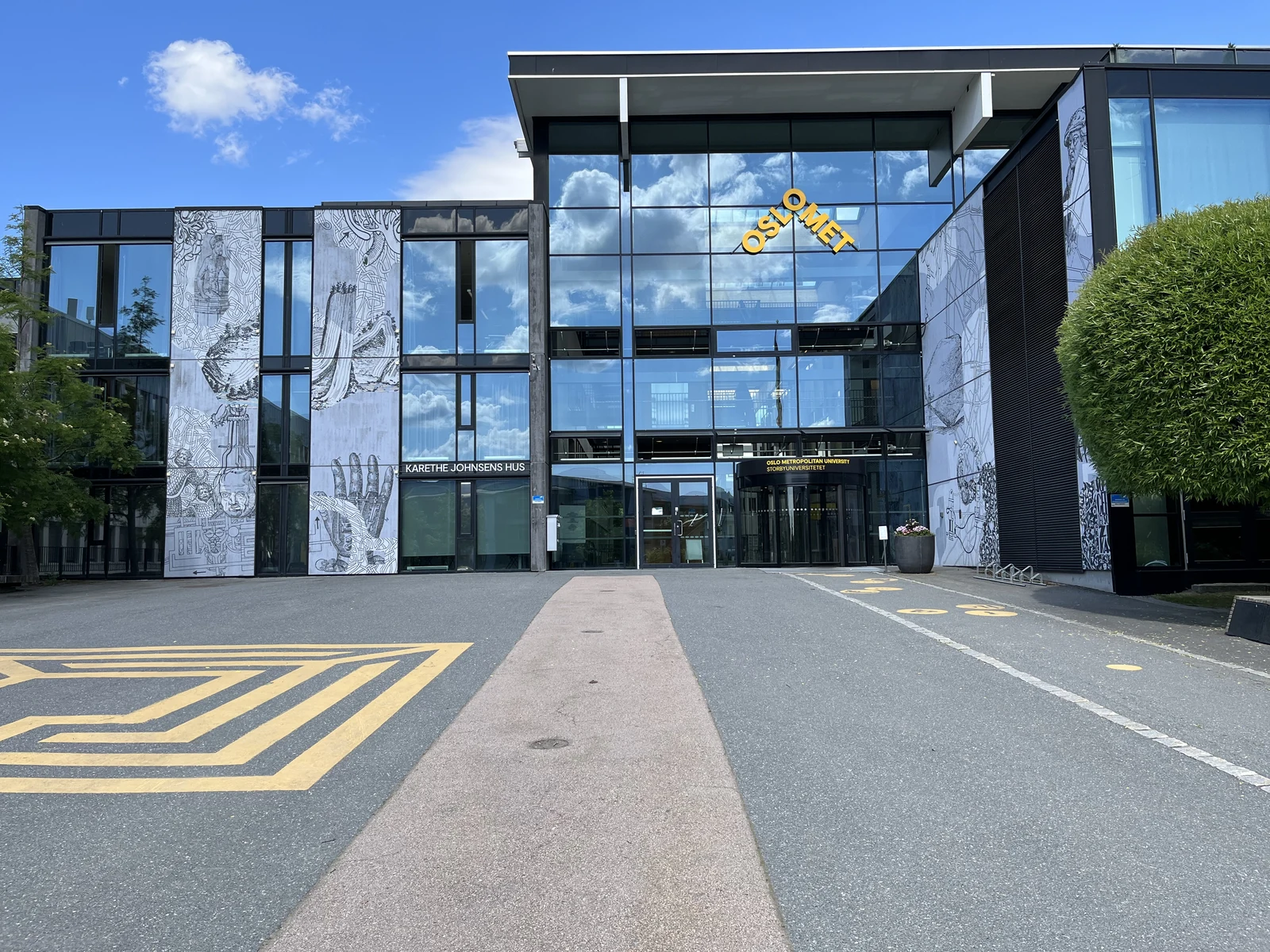 OsloMet Kjeller 校区的玻璃入口、校名与前方道路。